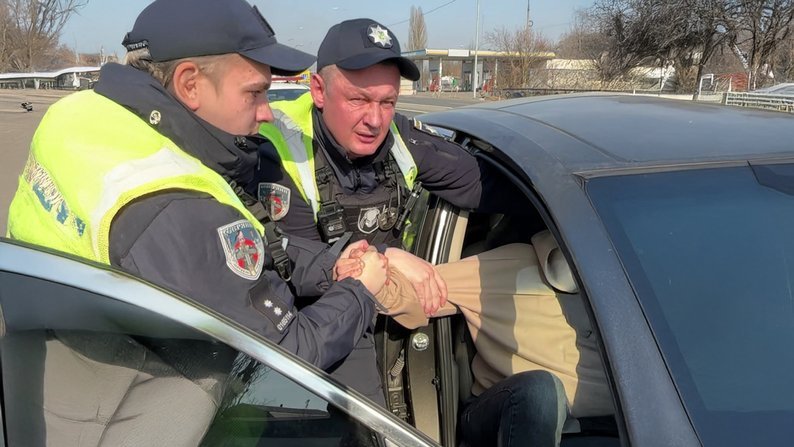 Патрульні тягнуть за руку чоловіка з автівки